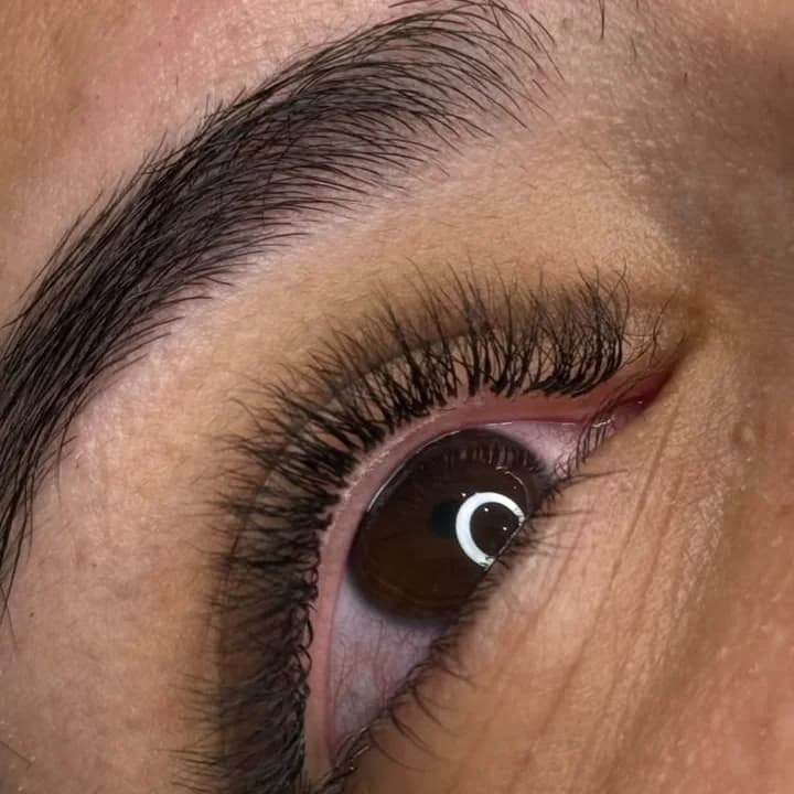 Close de um olho com extensão de cílios volumosa e a sobrancelha bem definida.